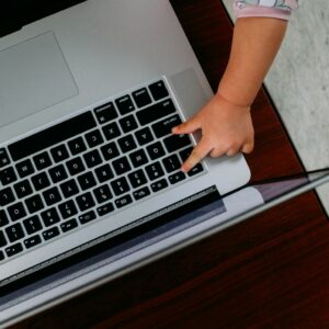 person using macbook pro on brown wooden table